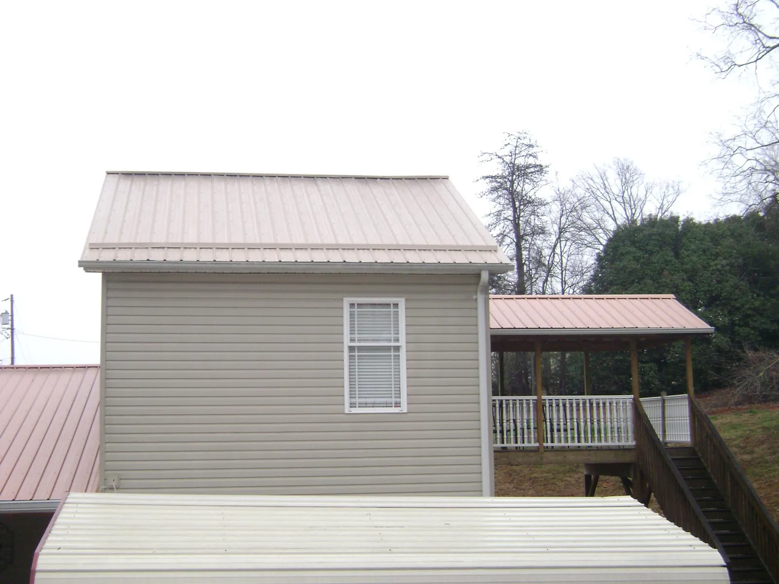 Tan metal roofs on a two story addition and attached porch, from a Roof Replacement job in Park City